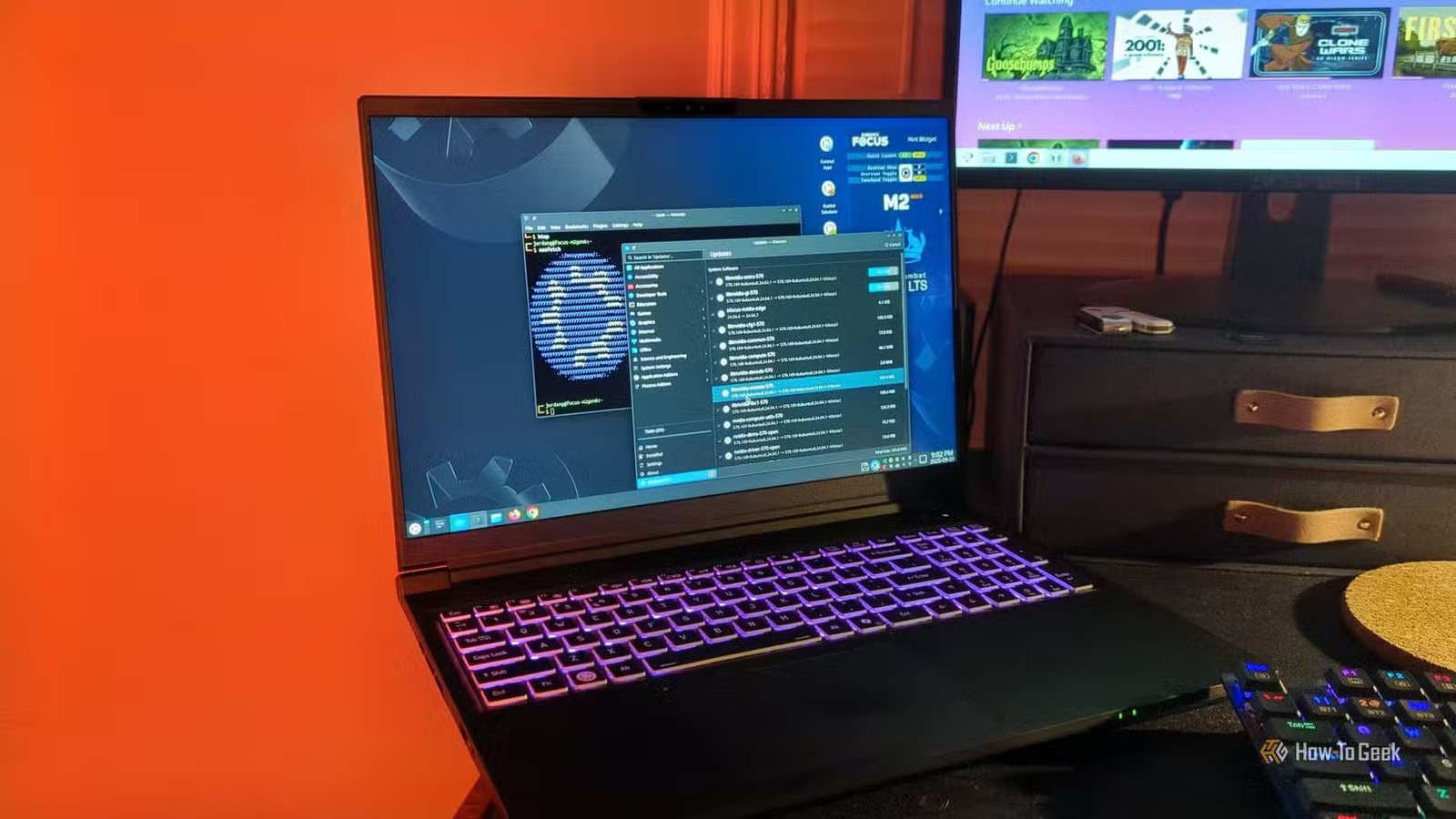 L'ordinateur portable Kubuntu Focus M2 Gen 6 sur un bureau avec un programme de mise à jour du logiciel et un terminal Linux ouvert.