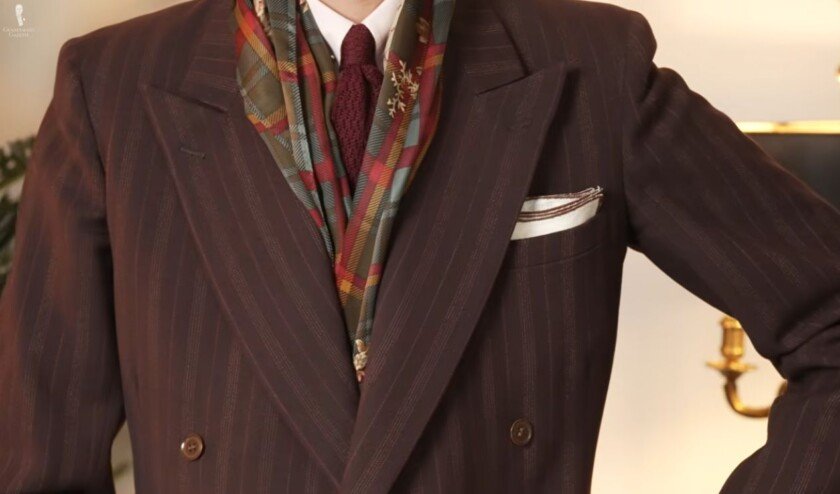 Foulard en soie avec costume et cravate Gros plan d'un homme portant un foulard en soie à motifs avec un costume croisé à fines rayures et une cravate en tricot
