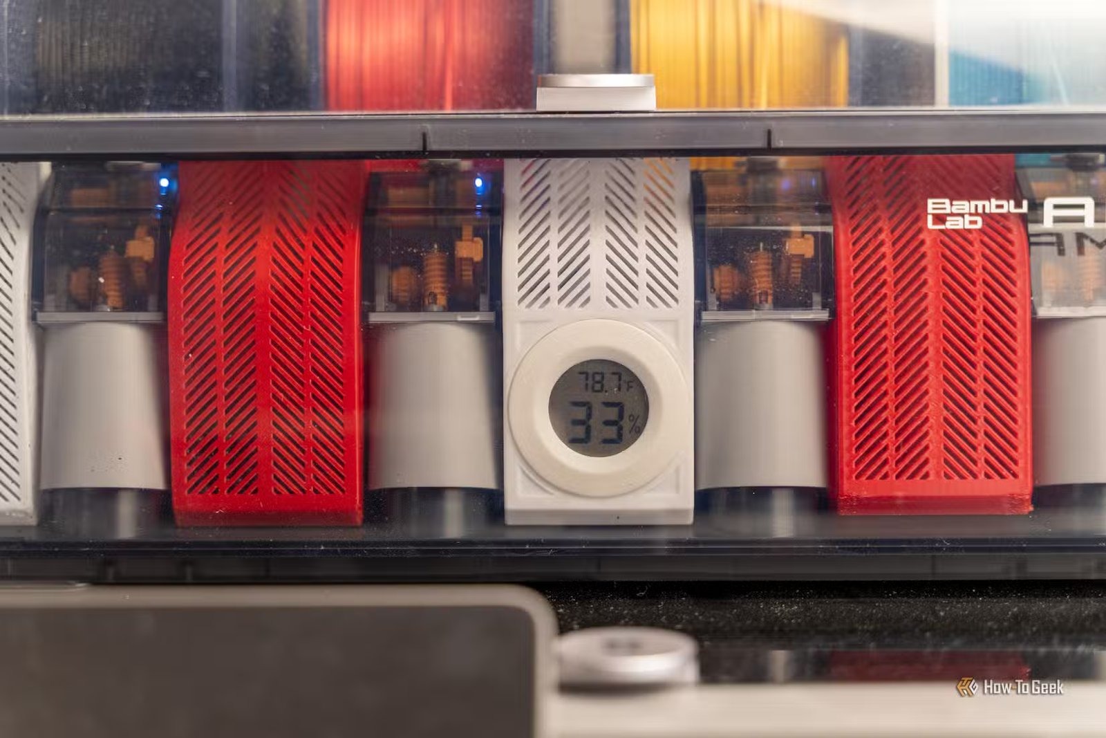 L'unité Bambu Lab AMS avec filament et déshydratant montrant un hygromètre pour l'humidité et le pourcentage d'humidité.