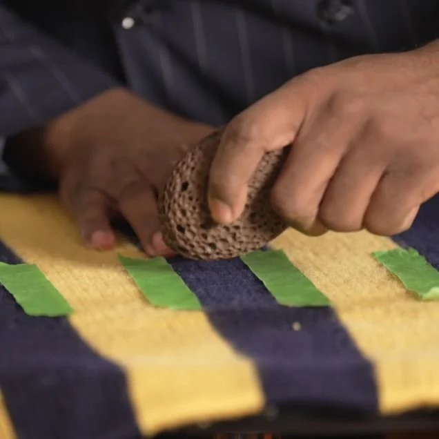 Test d'élimination des pilules de pierre ponce Pierre ponce frottée doucement sur un pull en laine pour éliminer les bouloches de tissu lors d'un test de déboulochage.