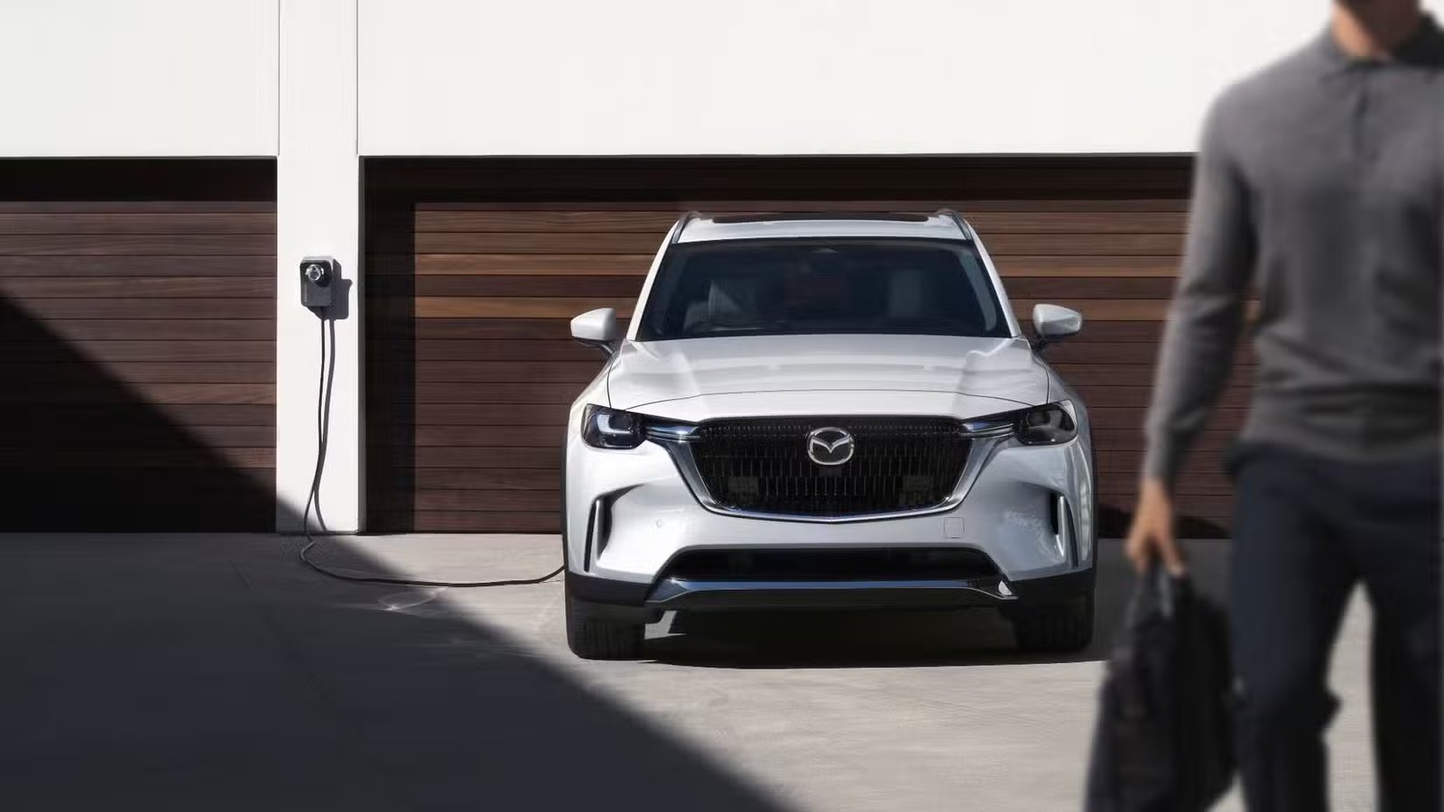 Photo statique de l'avant d'un Mazda CX-90 PHEV 2026 blanc branché en charge.