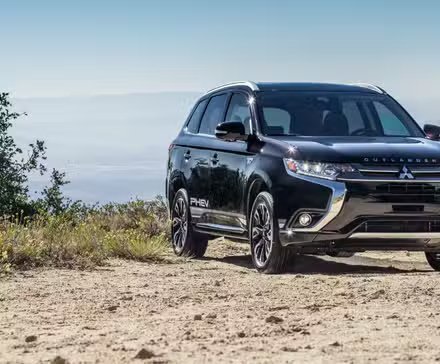 Vue avant du Mitsubishi Outlander PHEV 2018 noir garé sur du gravier.
