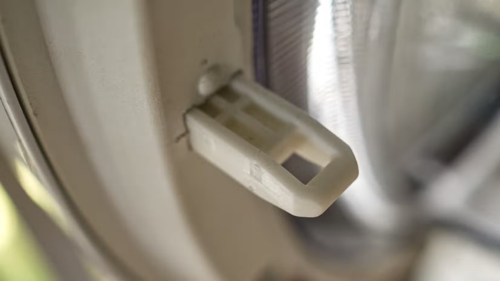 Un loquet en plastique fragile sur un sèche-linge.-1