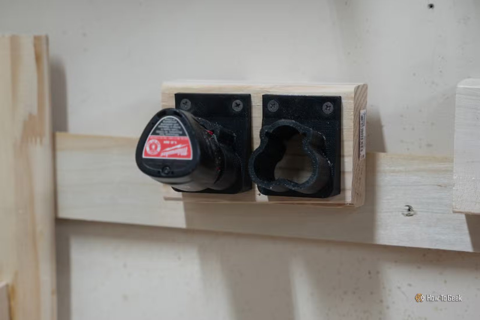 Deux supports de batterie Milwaukee M12 imprimés en 3D avec une batterie insérée et une vide.