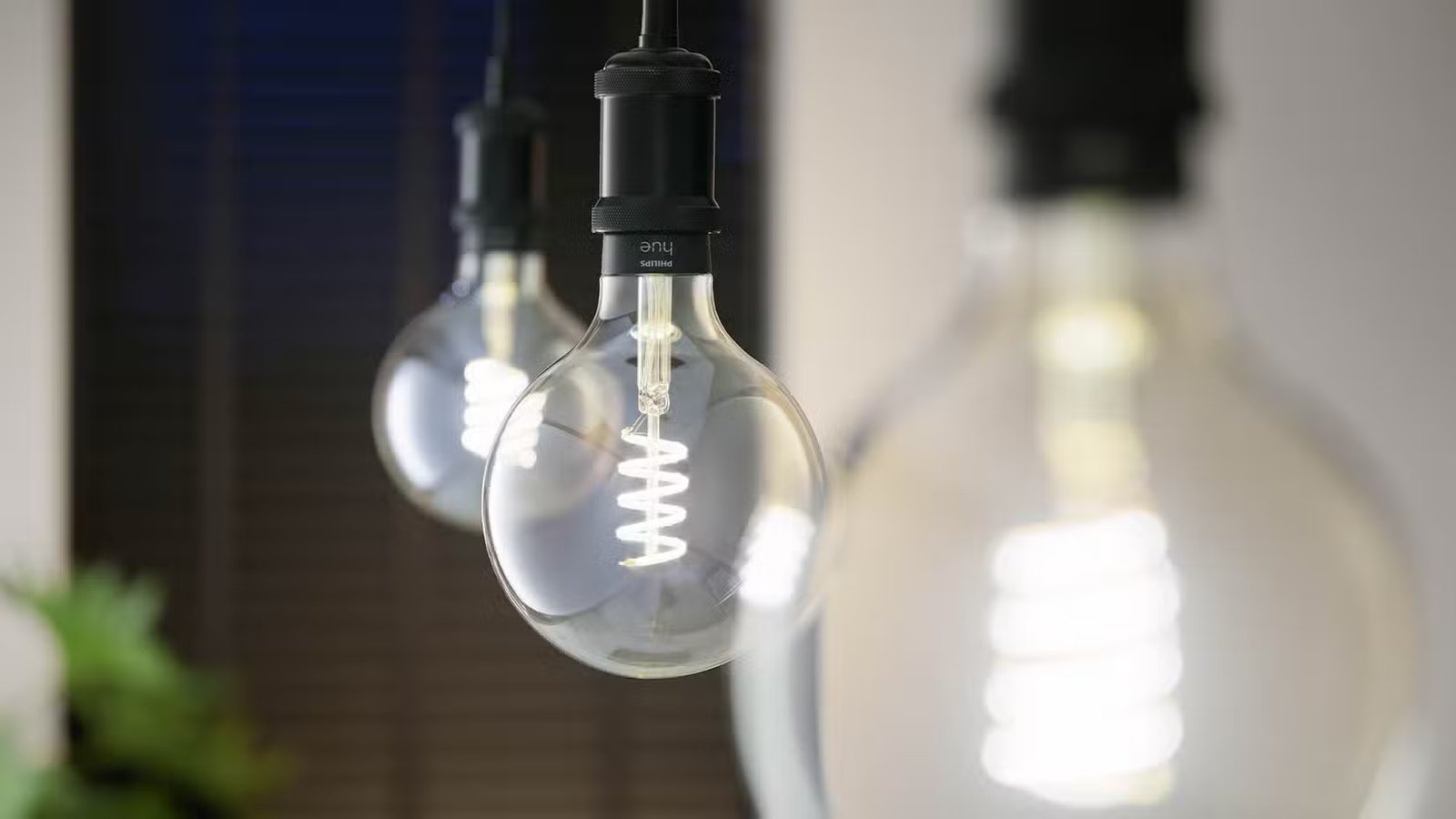 Trois ampoules à filament Philips Hue G25 suspendues en rangée.