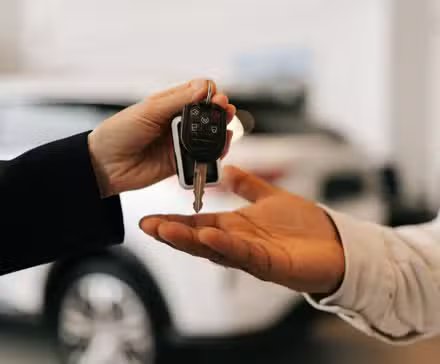 Gros plan sur la main d'un acheteur noir méconnaissable obtenant la clé de la voiture et les salutations du concessionnaire automobile lors de l'achat d'une nouvelle voiture chez le concessionnaire.
