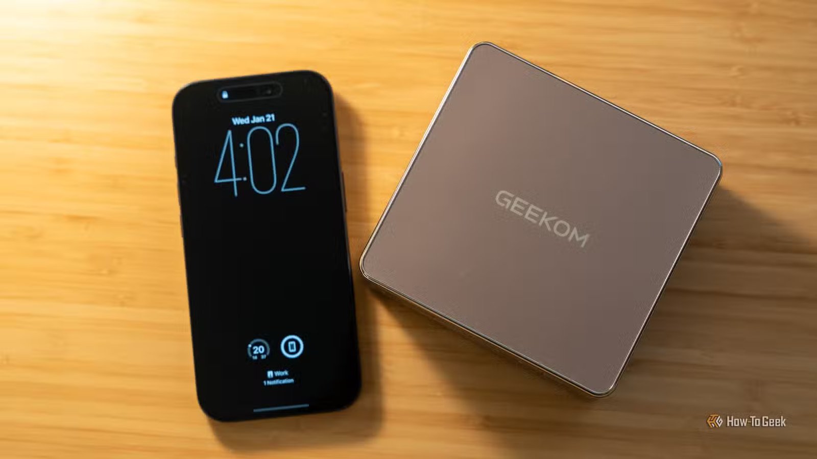 Le mini PC GEEKOM A5 assis à côté d’un iPhone 17 Pro pour montrer la comparaison des tailles.