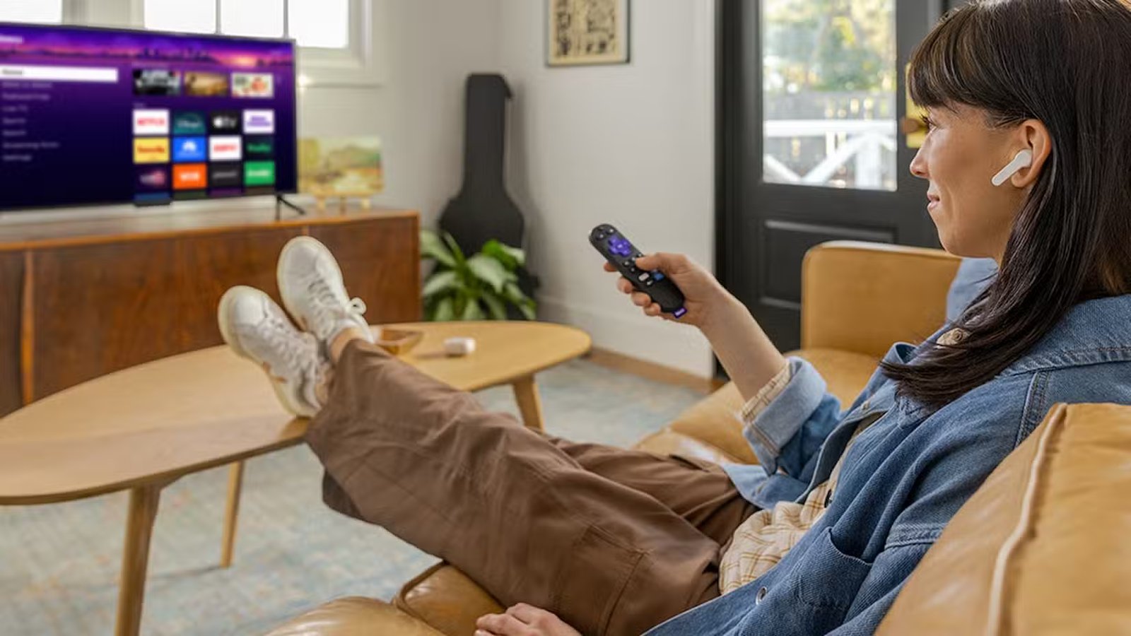 Quelqu'un assis sur le canapé regarde une télévision Roku avec des écouteurs