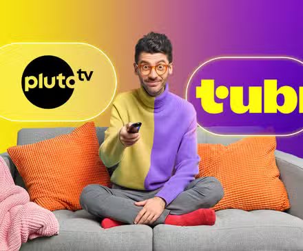 Un gars sur son canapé tenant la télécommande du téléviseur avec les logos de Pluto TV et Tubi à côté de lui.