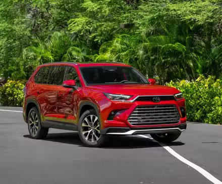 Plan statique 3/4 avant d'un Toyota Grand Highlander 2026 rouge.
