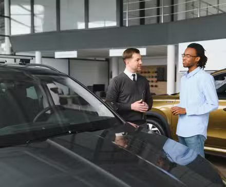 Conseiller commercial avec un client sur le stand d'exposition d'un concessionnaire automobile