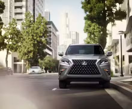 Une Lexus GX 460 argentée garée dans une rue le long d'un trottoir dans une ville.