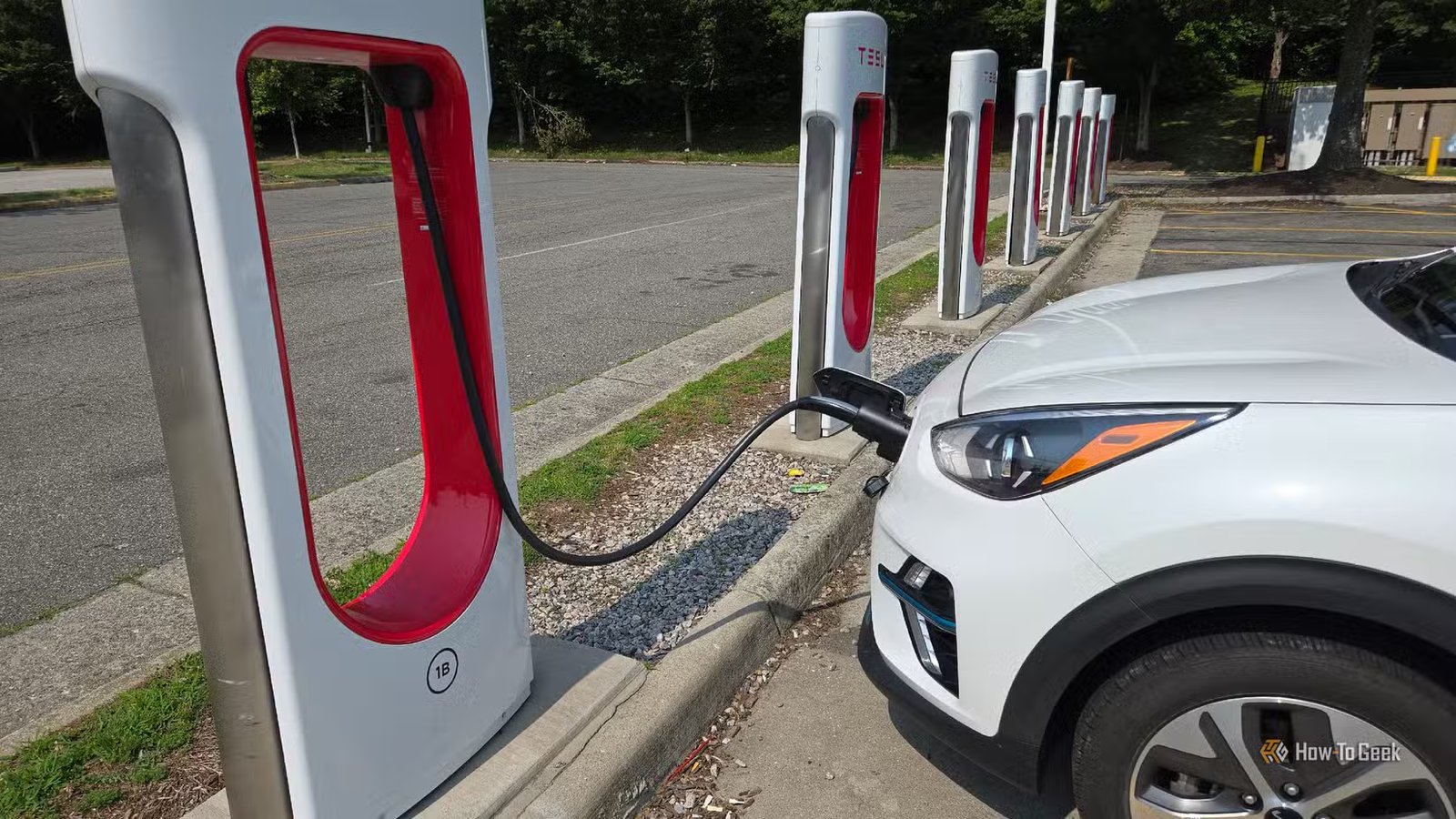 Un Kia Niro EV en charge sur un stand Tesla Supercharger.