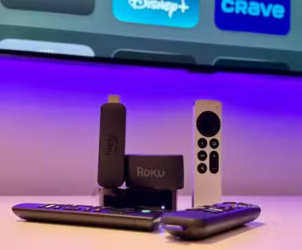 Une Apple TV 4K, un Fire TV Stick et un appareil de streaming Roku avec leurs télécommandes