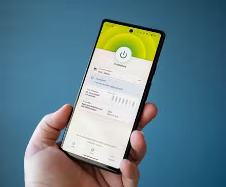Homme tenant un téléphone avec une application VPN affichant le statut « Connecté ».