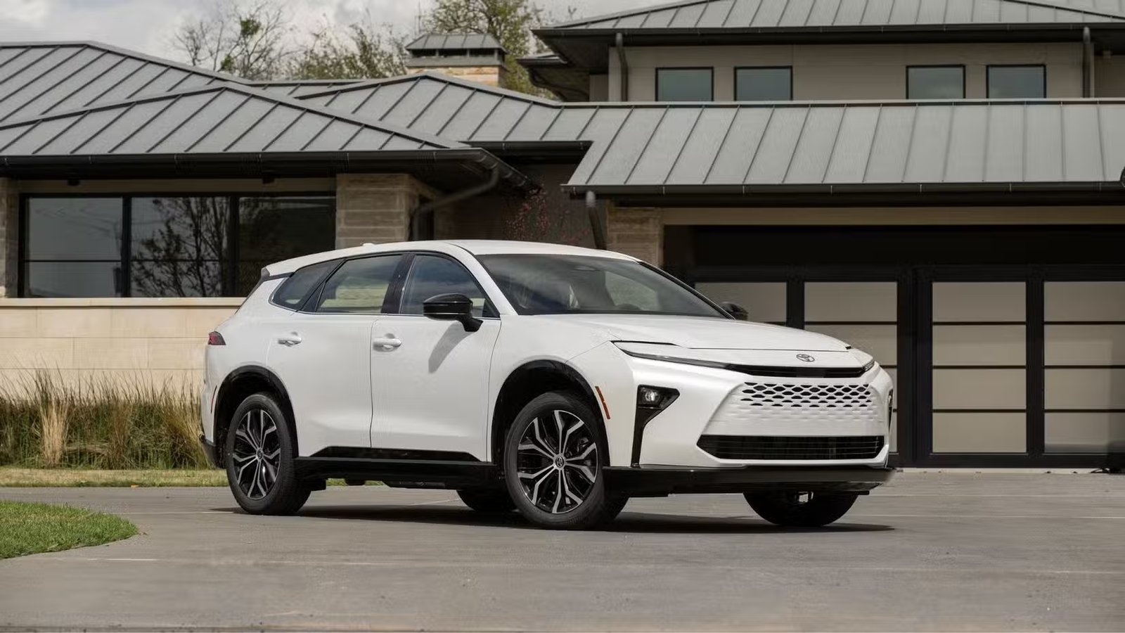 Plan Frotn 3/4 d'une Toyota Crown Signia XLE 2025 blanche garée à l'extérieur d'un bâtiment.