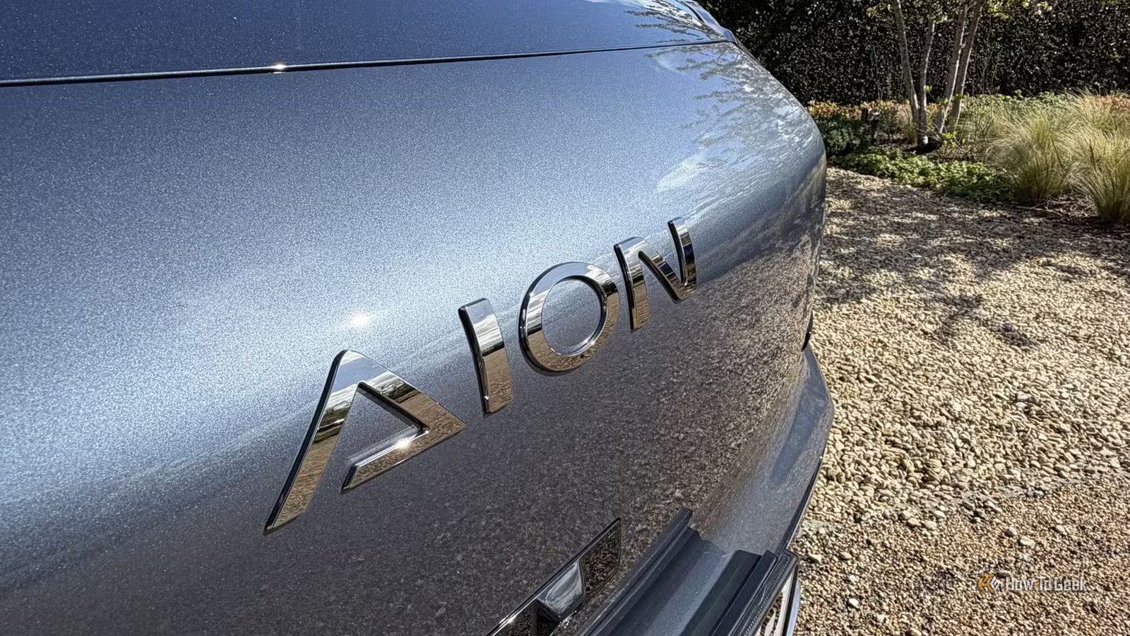 Gros plan du badge « AION » sur le devant d'un AION V gris.