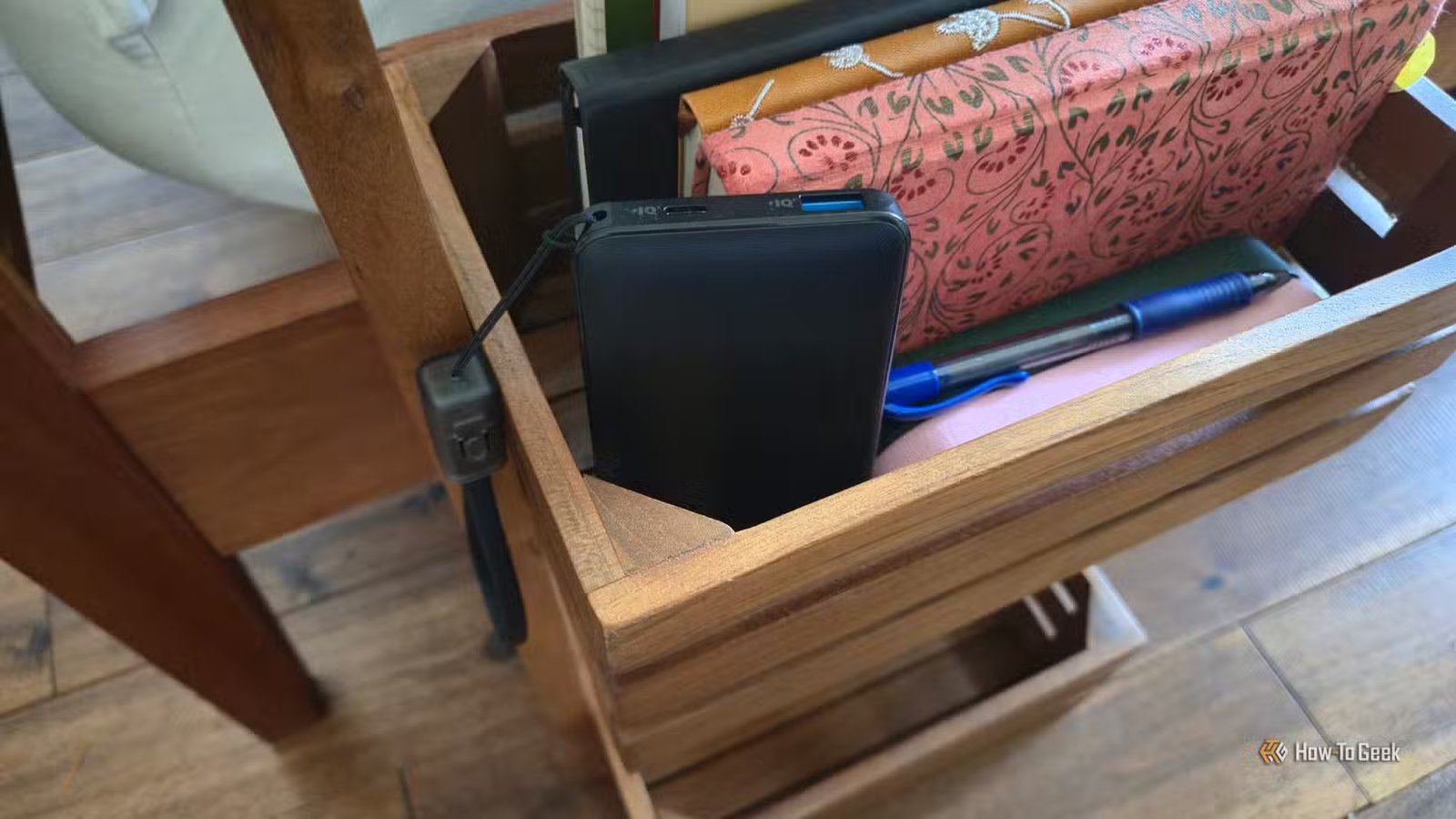 Une banque d'alimentation portable Anker dans un panier à côté d'un lit.