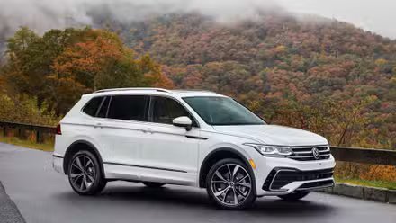 Vue de trois quarts avant d'un Volkswagen Tiguan 2024 blanc garé sur le bord de la route dans les montagnes.