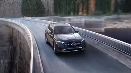 Plan dynamique 3/4 avant d'un Mercedes-Benz GLC 2025 noir roulant sur un pont.