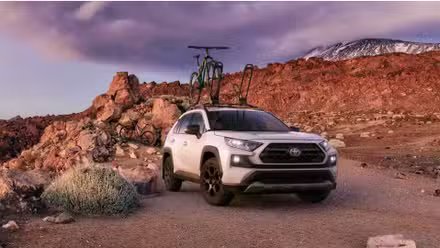 Toyota RAV4 2020 tout-terrain blanc avec un vélo sur le toit.