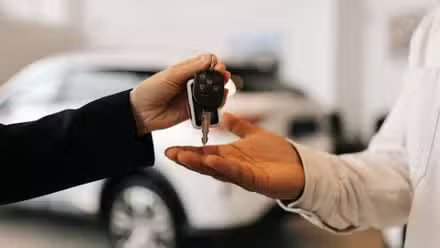 Gros plan sur la main d'un acheteur noir méconnaissable obtenant la clé de la voiture et les salutations du concessionnaire automobile lors de l'achat d'une nouvelle voiture chez le concessionnaire.
