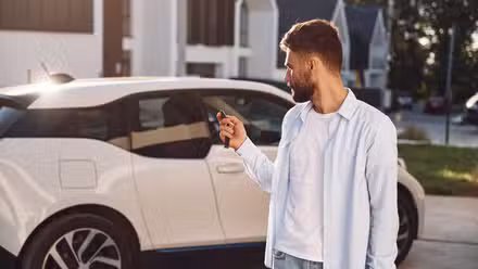 Jeune homme verrouillant une voiture dans l’allée