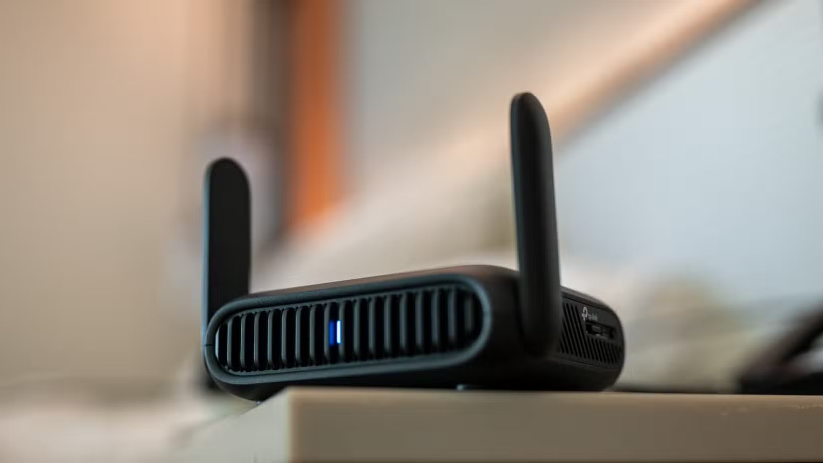 Routeur de voyage Wi-Fi TP-Link BE3600 posé sur une table dans une chambre d'hôtel.