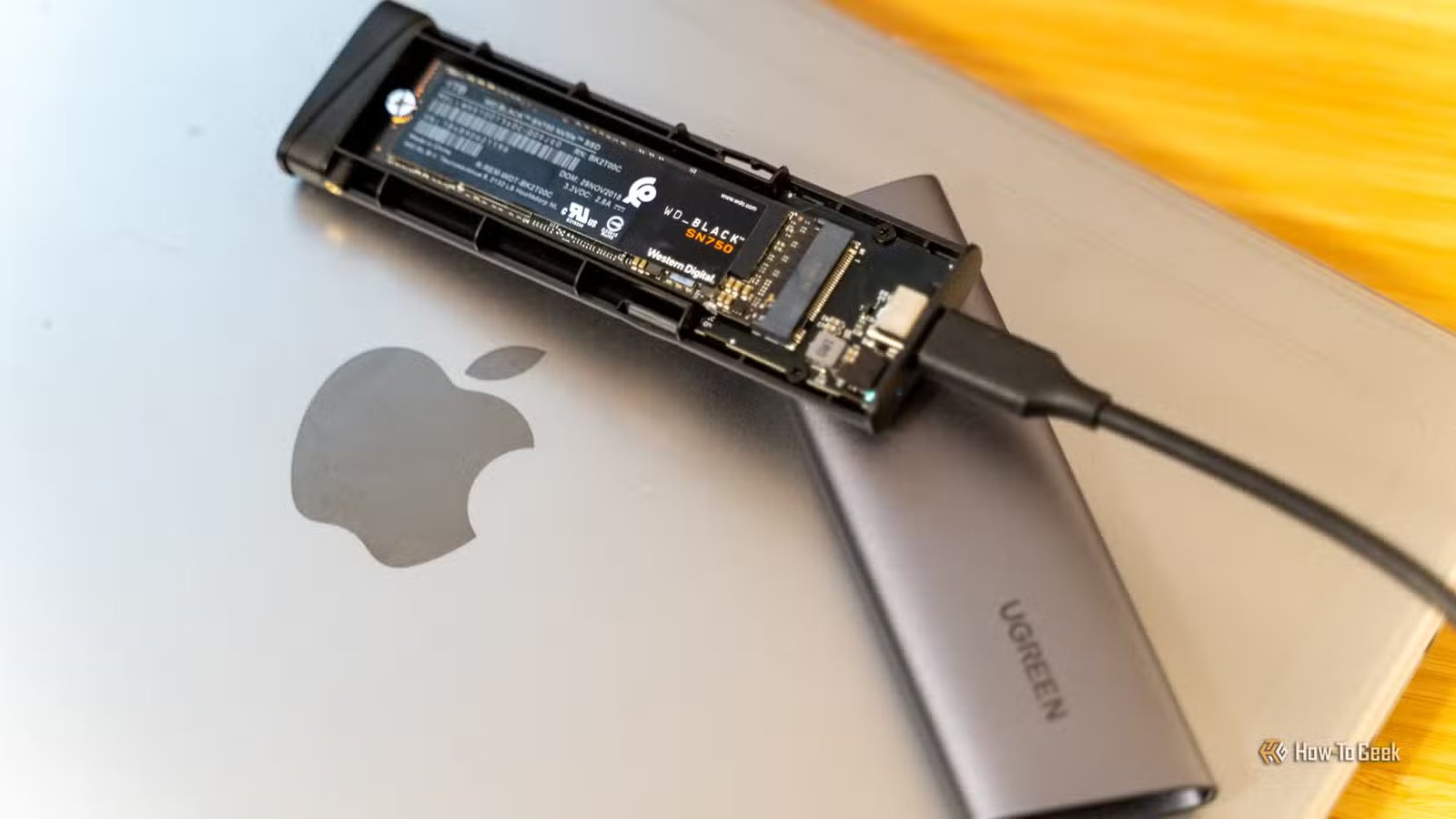 Boîtier UGREEN M.2 NVMe SSD USB-C avec SSD WD_BLACK SN750 à l'intérieur assis sur un MacBook.