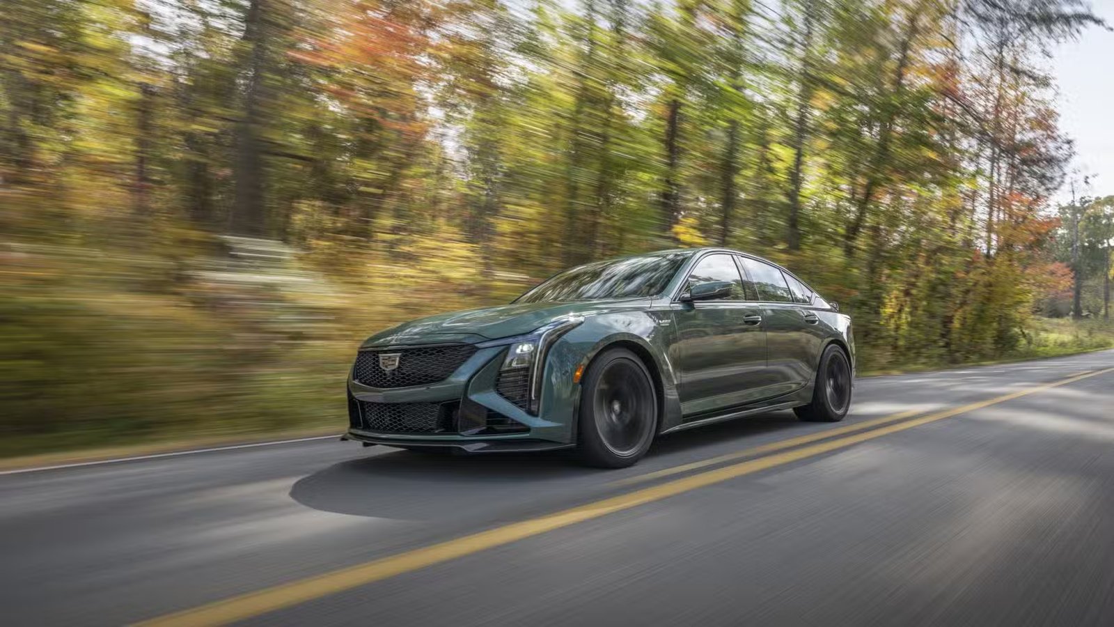 Plan dynamique 3/4 avant d'une Cadillac CT5-V Blackwing 2026 verte roulant sur une route de campagne.