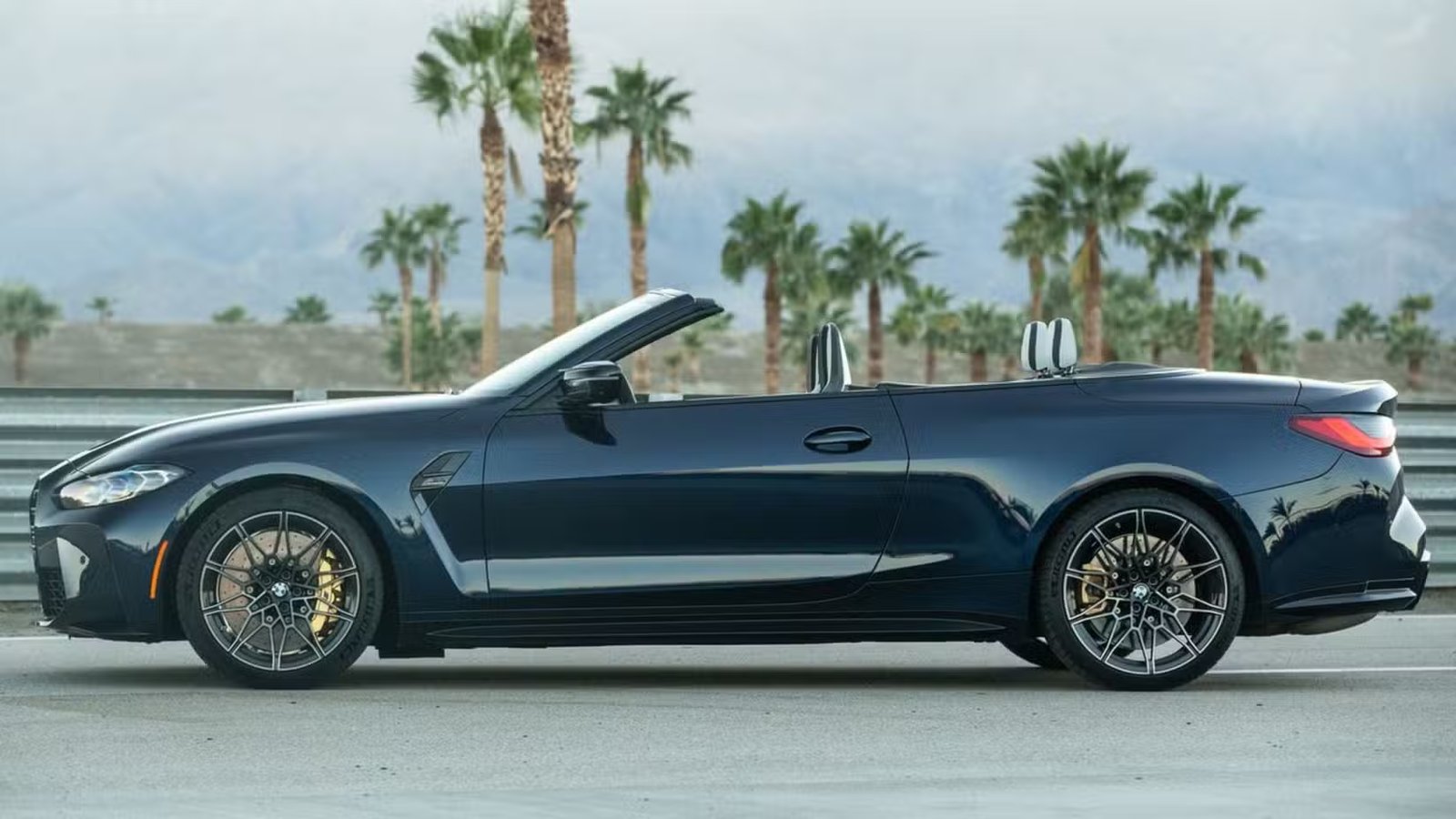 Photo de profil latérale statique d'une BMW M4 Competition Cabriolet xDrive 2022 noire.