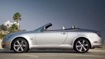 Photo de profil latérale statique d'une Lexus SC 430 2010 argentée garée sur une plage.