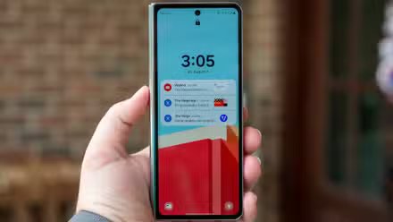 Personne tenant le Samsung Galaxy Z Fold 5 fermé avec l’écran de verrouillage de l’écran avant allumé