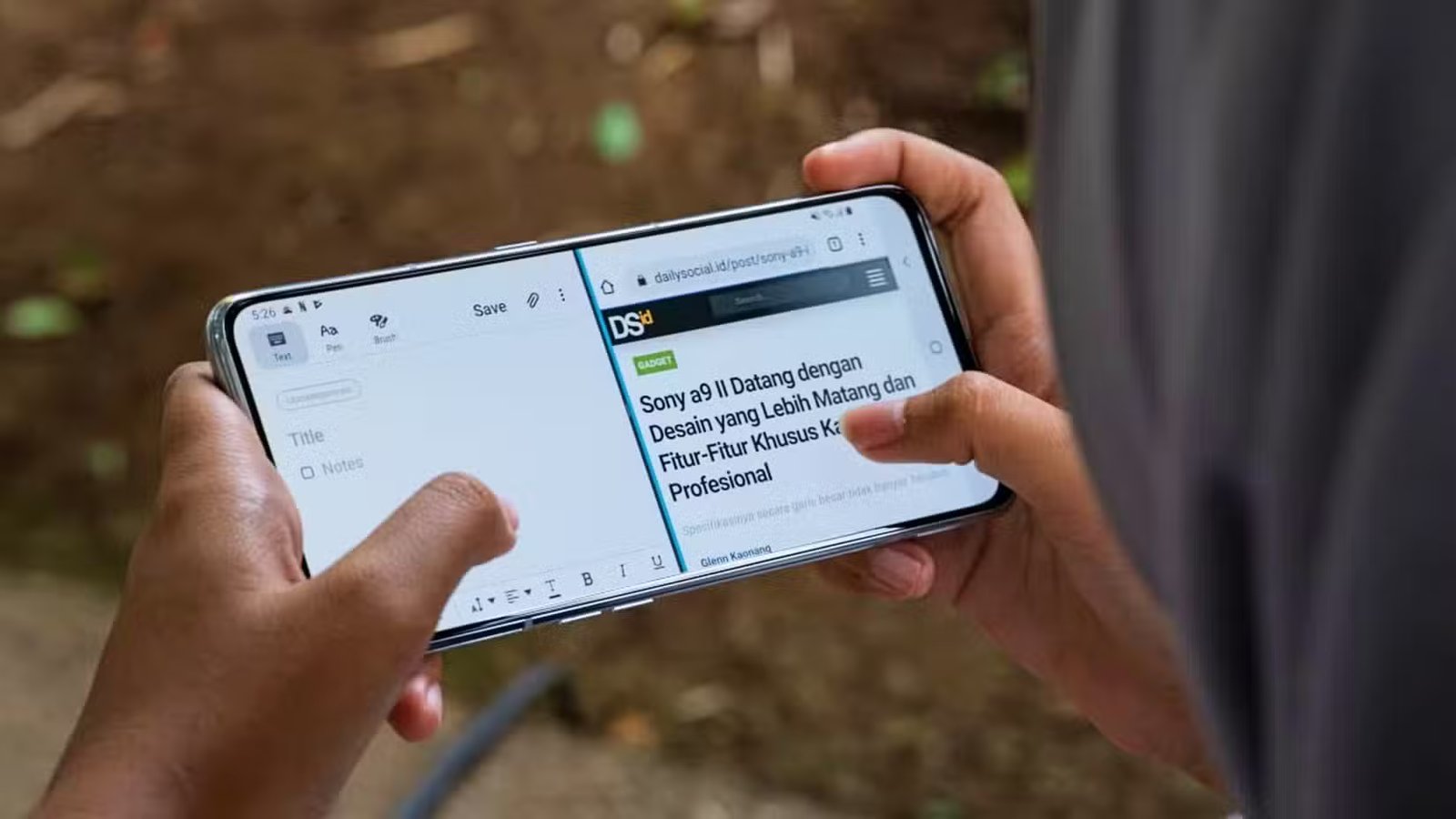 Mains d'une personne tenant un téléphone Android et l'utilisant en mode écran partagé.