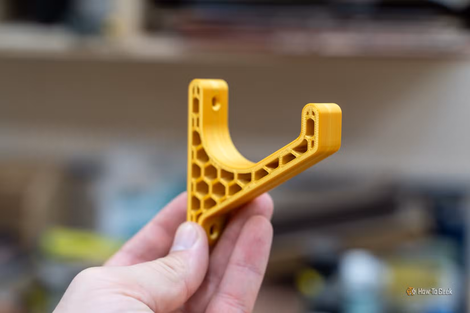 Support d'atelier jaune imprimé en 3D avec remplissage en nid d'abeille tenu à la main.