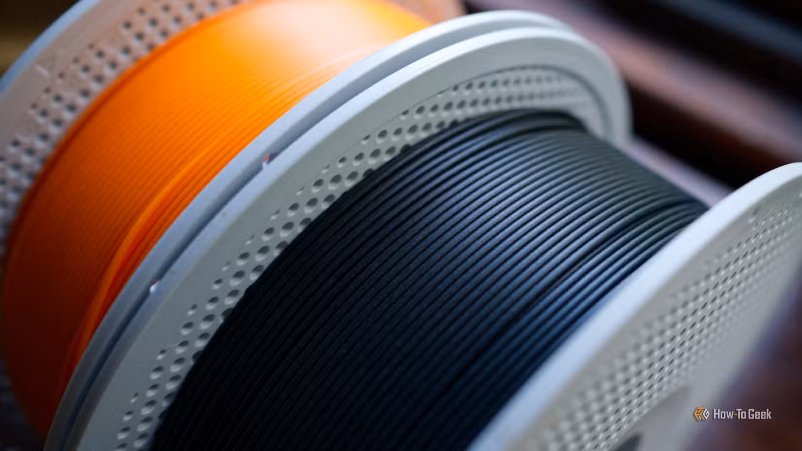 Un rouleau de filament d'imprimante 3D PLA noir mat et PLA orange basique.