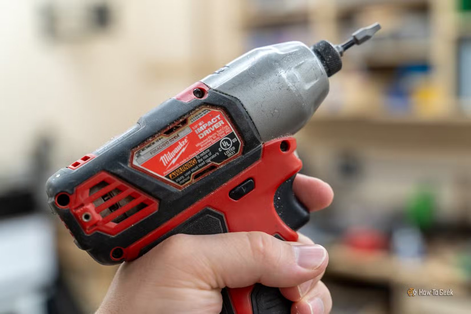 Gros plan d'un tournevis à percussion hexagonal d'un quart de pouce Milwaukee M12 à la main.