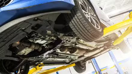 Voiture bleue sur un ascenseur dans un magasin, montrant le dessous de caisse.