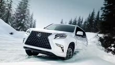 Un Lexus GX 2022 blanc roulant dans la neige dans une zone boisée.