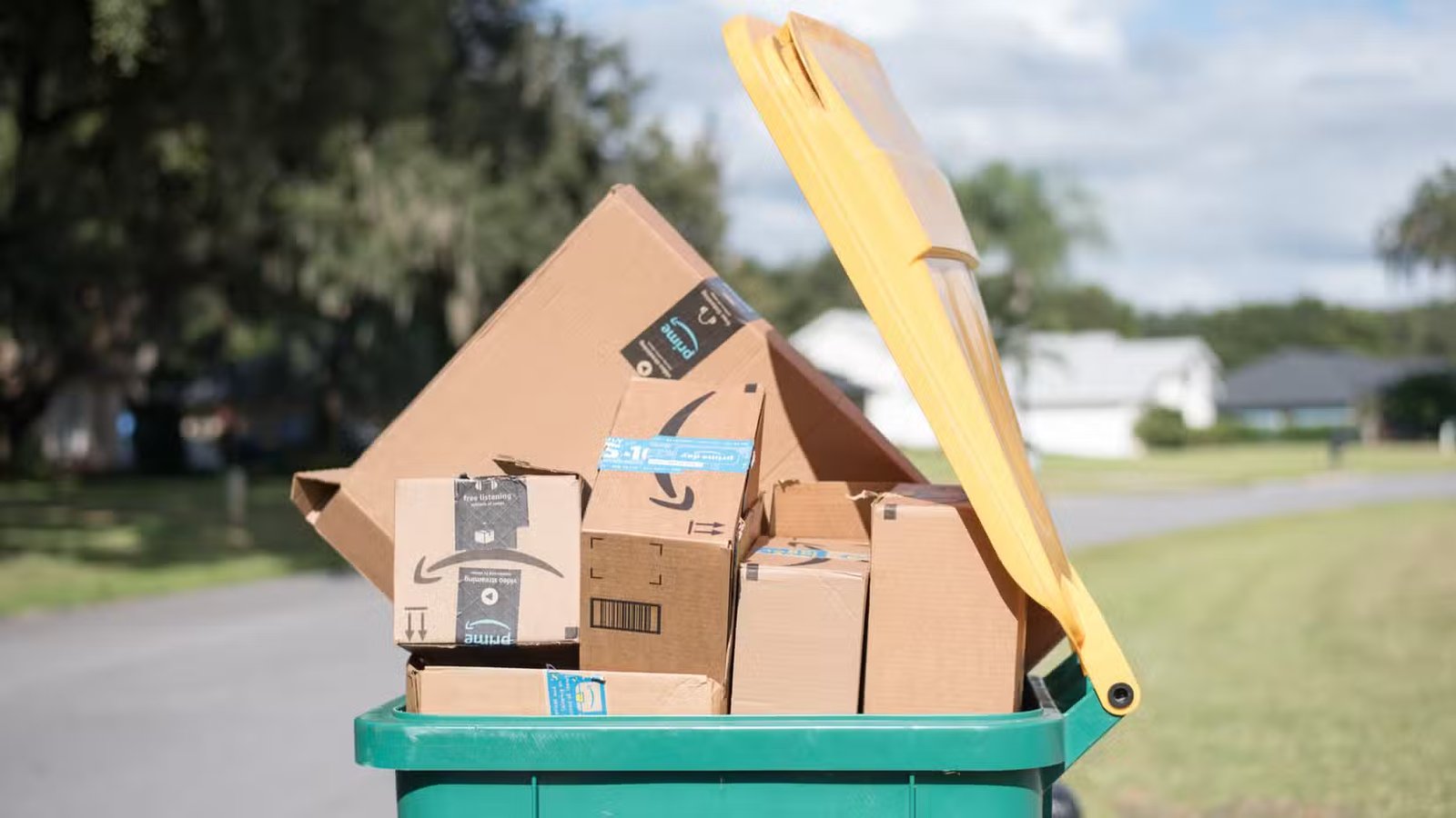 Des cartons Amazon empilés dans une poubelle. 