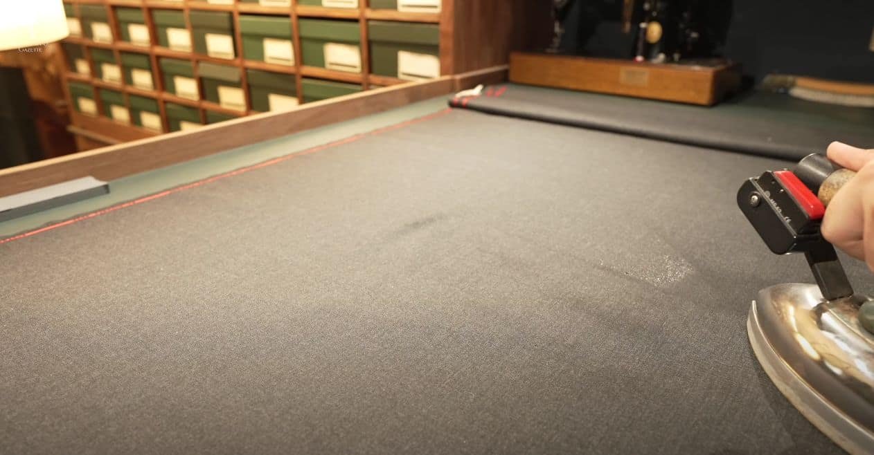 une main utilisant un fer vintage sur le tissu du costume