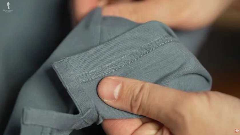 Gros plan sur les coutures du polo Raphaël inspecte les coutures d'un polo