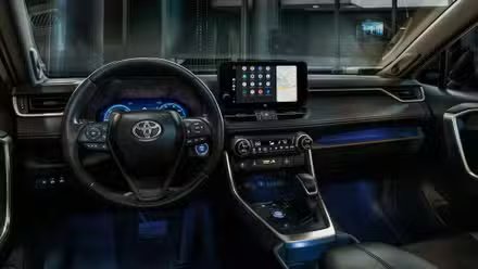 Gros plan du tableau de bord d'un Toyota RAV4 2024 de nuit avec son éclairage ambiant.