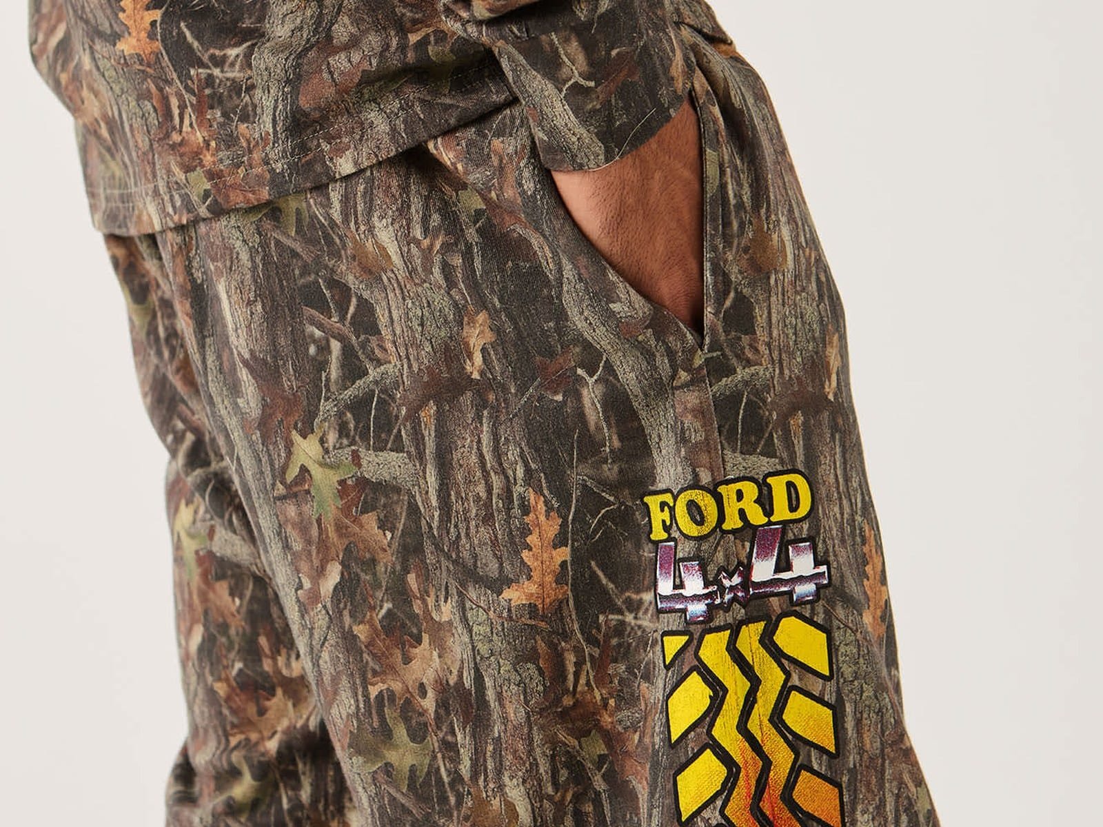 Gros plan sur le graphisme de la bande de roulement du pneu Ford 4x4 sur le pantalon de survêtement chromé en camouflage vert buis