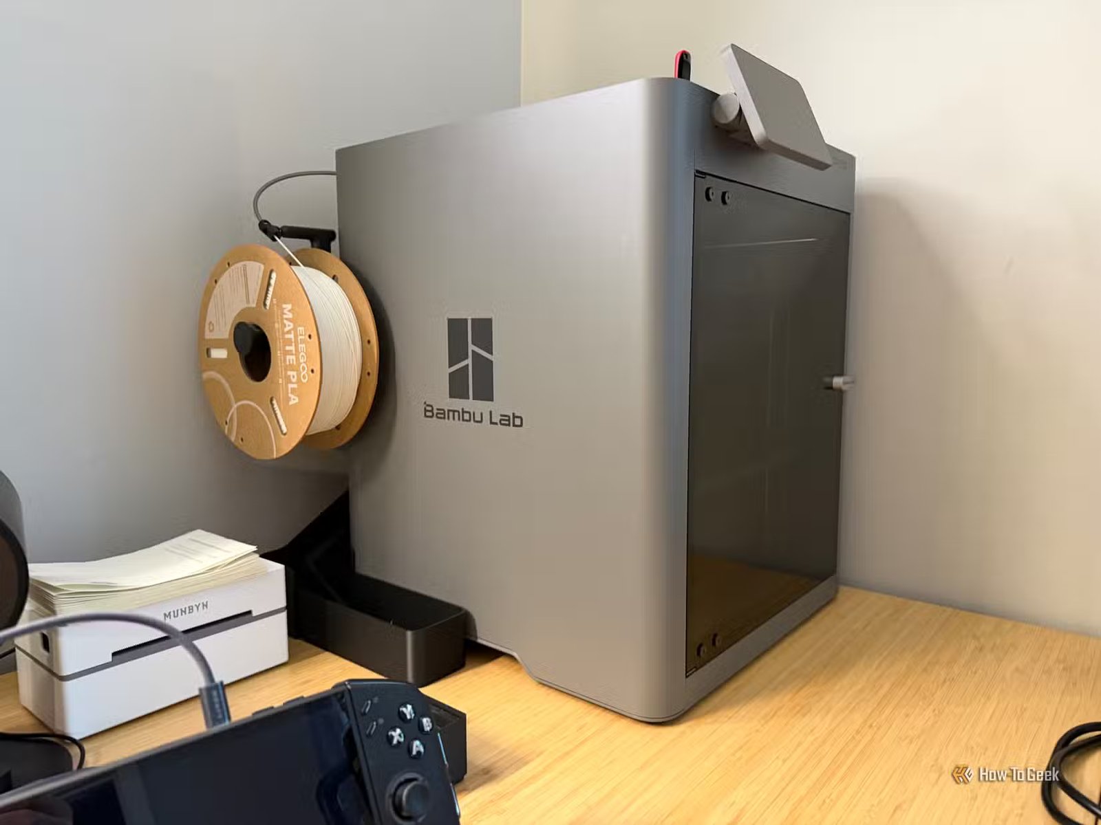 Le Bambu Lab P2S posé sur un bureau avec une bobine de filament blanche sur le côté.