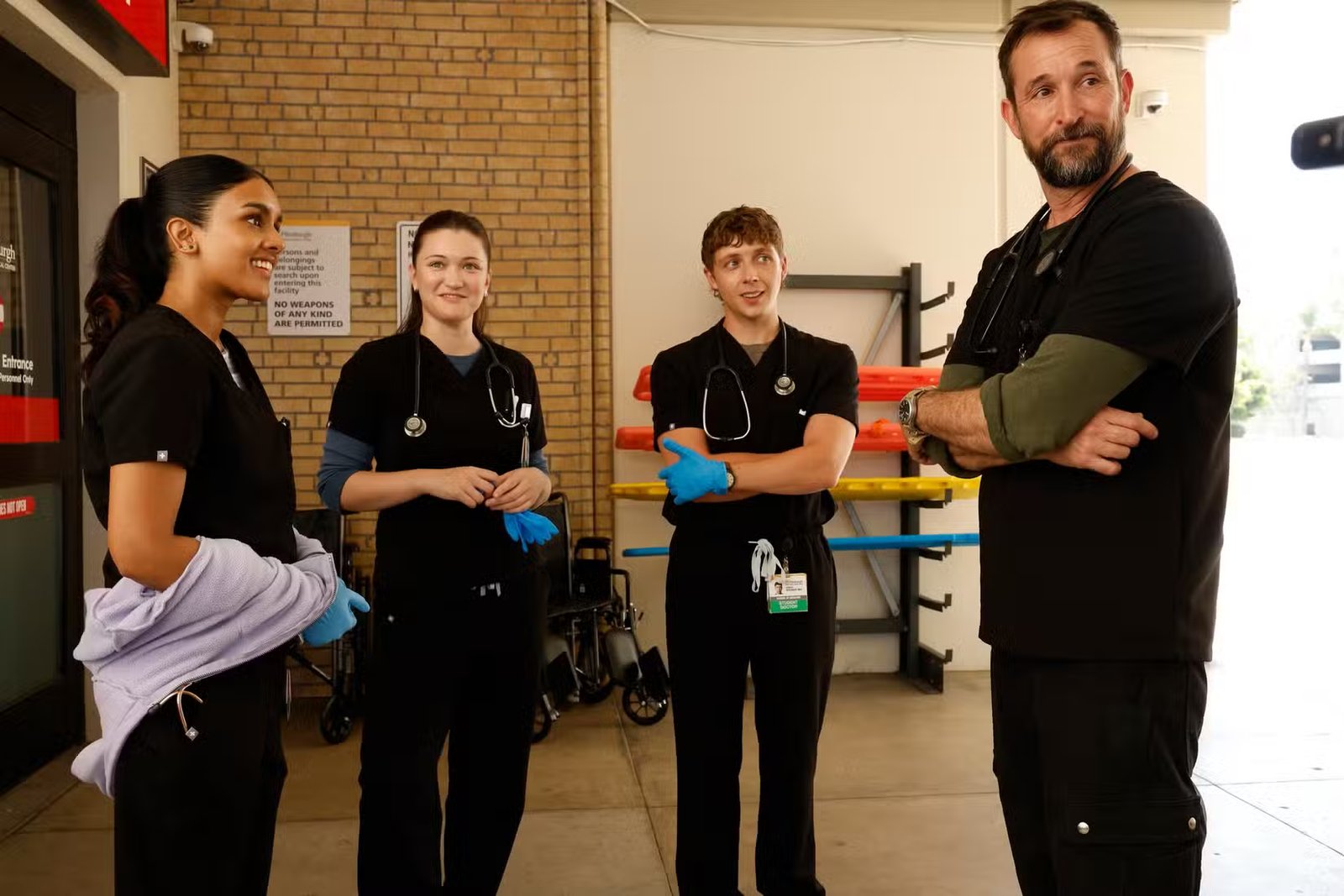 Shabana Azeez, Isa Briones, Gerran Howell et Noah Wyle debout à l'extérieur de l'urgence, en blouse et gants, dans The Pitt S2.