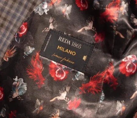 Vidéo Highlight 4 Doublure florale Reda Doublure de veste noire audacieuse à motifs de fleurs rouges, de plumes et de gibier à plumes, avec une étiquette Reda cousue. Le texte dit : "Tissus emblématiques REDA 1865 MILANO. Tissu fabriqué en Italie."