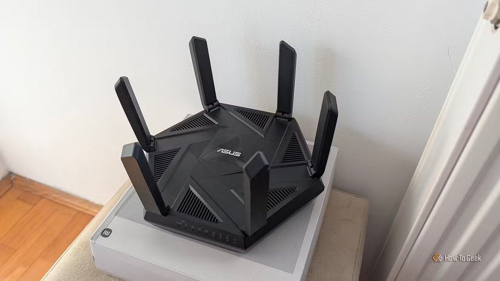 Un routeur ASUS Wi-Fi 6E placé sur un boîtier près d'une porte contre le mur.