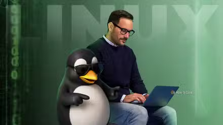 Un homme utilisant un ordinateur portable à côté de Tux, la mascotte Linux, portant des lunettes de soleil.