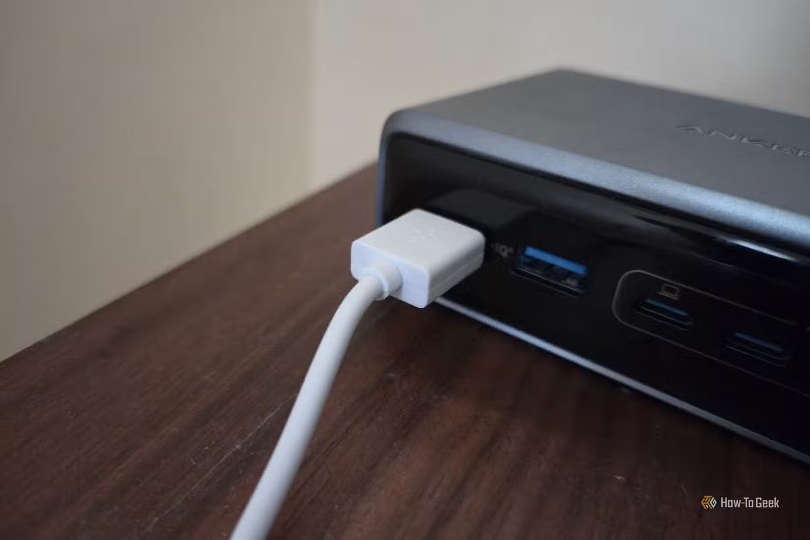 Câble USB blanc branché sur une station de recharge Anker.